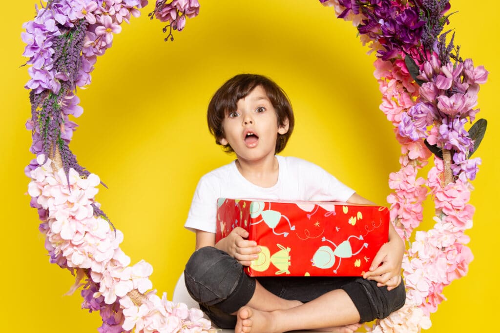 front view surprised boy with red designed present white t shirt yellow floor